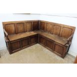 An 18th century oak church corner pew with panelled back and open arm supports