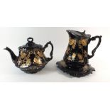 A 19th century Staffordshire Jackfield style black and gilt pottery teapot and matching jug by