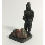 An Inuit stone carving of a man carving stone, from Paamiut in Greenland signed Ole Lorenizen 8.5cm
