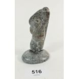 An Inuit stone carving of Inuit man carrying a rock, signed DKK from Cape Dorset, Baffin Island,