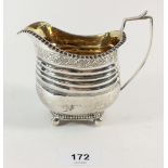 A Georgian silver milk jug with engraved vine border, reeded body and ball feet, 9.5cm high, 169.3g