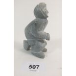 A stone carving of an Inuit man sitting on a rock, signed M Abt from Paamiut Greenland