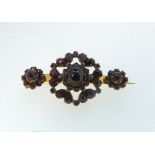 A Victorian yellow metal brooch set three garnet clusters