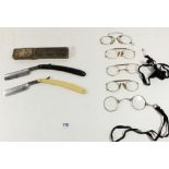 A silver pair of spectacles and four pairs of gold plated spectacles, a cut throat razor with box,