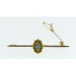 An Edwardian gold bar brooch set blue stone flanked by two diamonds, 3.9g