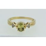 A 9ct gold ring set central peridot and flanking diamond chips, size N, 2.2g