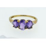 A 9ct gold ring set with three amethysts, size O, 1.6g