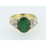 An 18 carat gold ring set oval cut emerald flanked by six diamonds, size M/N, 7g