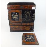 A Japanese lacquer and marquetry table top cabinet with rise top over doors and drawers, one door