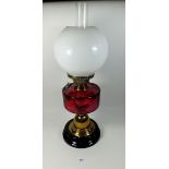 A Victorian oil lamp with cranberry glass reservoir