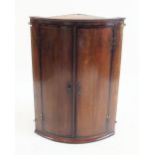 A Georgian oak bow fronted corner cabinet with brass butterfly hinges, 92cm