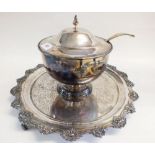 A silver plated circular tray with cast floral border and a silver plated tureen with ladle