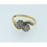 An 18 carat gold ring cross over illusion set with two diamonds on diamond chip shoulders, size P