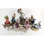 A group of eight figurines to include children on seesaw, woman walking dog with umbrella, boy in