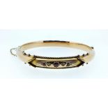 An Edwardian 9 carat gold hinged bangle inset rubies and chip diamonds, 8.2g