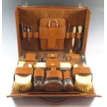 An early 20th century leather cased gentleman's toiletry case fitted with silver topped glass