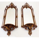 A pair of 19th century gilt wood girandole mirrors with putti and floral surmont and bird and husk