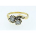 An 18 carat gold ring cross over illusion set with two diamonds on diamond chip shoulders, size P,