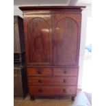 A 19th century mahogany linen press with arched doors enclosing trays over two short and two long