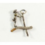 A miniature white metal moving charm with monkey sawing a log
