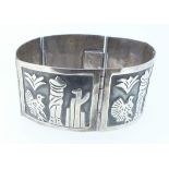 A Mexican silver hinged link bracelet with tongue and box clasp, the panels embossed with a