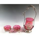 A cranberry glass jar on a silver plated stand and two similar salts (one a/f)
