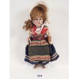 A small German porcelain headed costume doll with composition body, 21cm