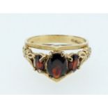 A 1970s 9ct gold garnet ring set with high cathedral setting decorated with hearts and scroll