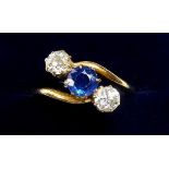 An 18 carat gold crossover ring set sapphire flanked by two diamonds, size N to O, size 3.5g