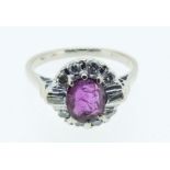 An 18 carat white gold ruby and diamond cluster ring with baguette and brilliant cut stones, size J
