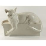 A white porcelain cat on plinth, 25cm across