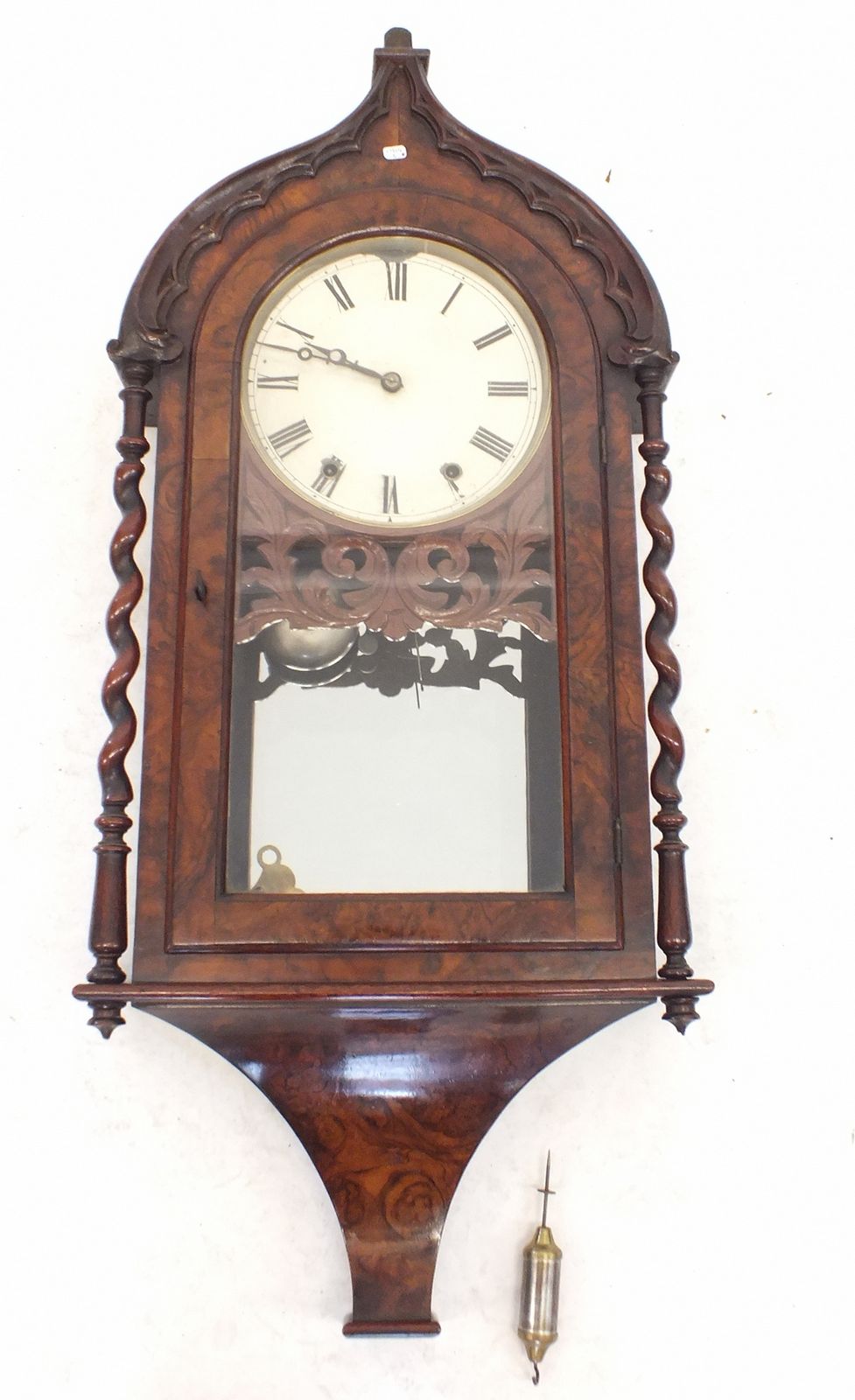 A Victorian walnut arch topped wall clock with pierced fretwork decoration, single glazed door and