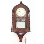 A Victorian walnut arch topped wall clock with pierced fretwork decoration, single glazed door and