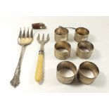 Six silver napkin rings, two silver plated forks, a silver cruet spoon and a white metal frog bottle
