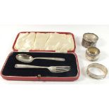 Three individual silver napkin rings and a silver fork and spoon set, gross weight 106g. Note -