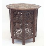 A Burmese octagonal occasional table carved vine leaves on folding stand