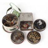 Five tins of miscellaneous military buttons; buckles; cap badges; epaulet rankings and travel mirror