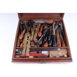 An antique mahogany case containing vintage tooling for leatherwork, etc