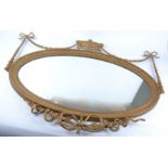 An oval giltwood mirror with swags and bows and covered urn decoration, height 90cm x 107cm AF in