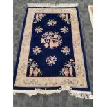 A Peking Oriental rug with precious objects and botanical sprays, on a dark blue ground, with