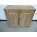 A waxed pine two door cupboard double panelled doors raised on bracket plinth, 93cm x 41cm x 87cm