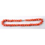 A polished coral necklace with near cylindrical beads, length 24cm