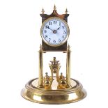 A 1930's brass torsion pendulum clock, white enamel dial with Arabic numerals, underneath a glass