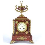 A 19th Century French red marble mantel clock, white enamel dial with Arabic numerals, flanked by