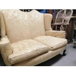 Two seater upholstered wing back settee, set on claw and ball feet to the front. Floor to cushion
