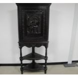 A stained oak carved 20th century corner cupboard on stand, top section having a moulded cornice,