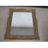 A swept framed wall mirror, antique gilded gesso frame with a contemporary glass plate, 88cm x 100cm