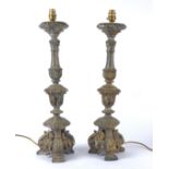 A pair of early 20th Century gilt cast plaster lamp bases, raised on three scrolling feet, with