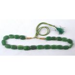 An Asian green hardstone bead necklace each section in the form of a leaf, on a gilt and green