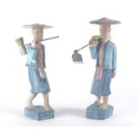 A pair of carved wooden figures, modelled as Asian farmworkers, each dressed in traditional clothing